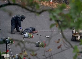 A bomb disposal technician collects evidence near the body of a man, believed to be the terrorist, at the scene of a deadly attack outside a synagogue, in north Manchester, Britain, October 2, 2025. (REUTERS/Hannah McKay)